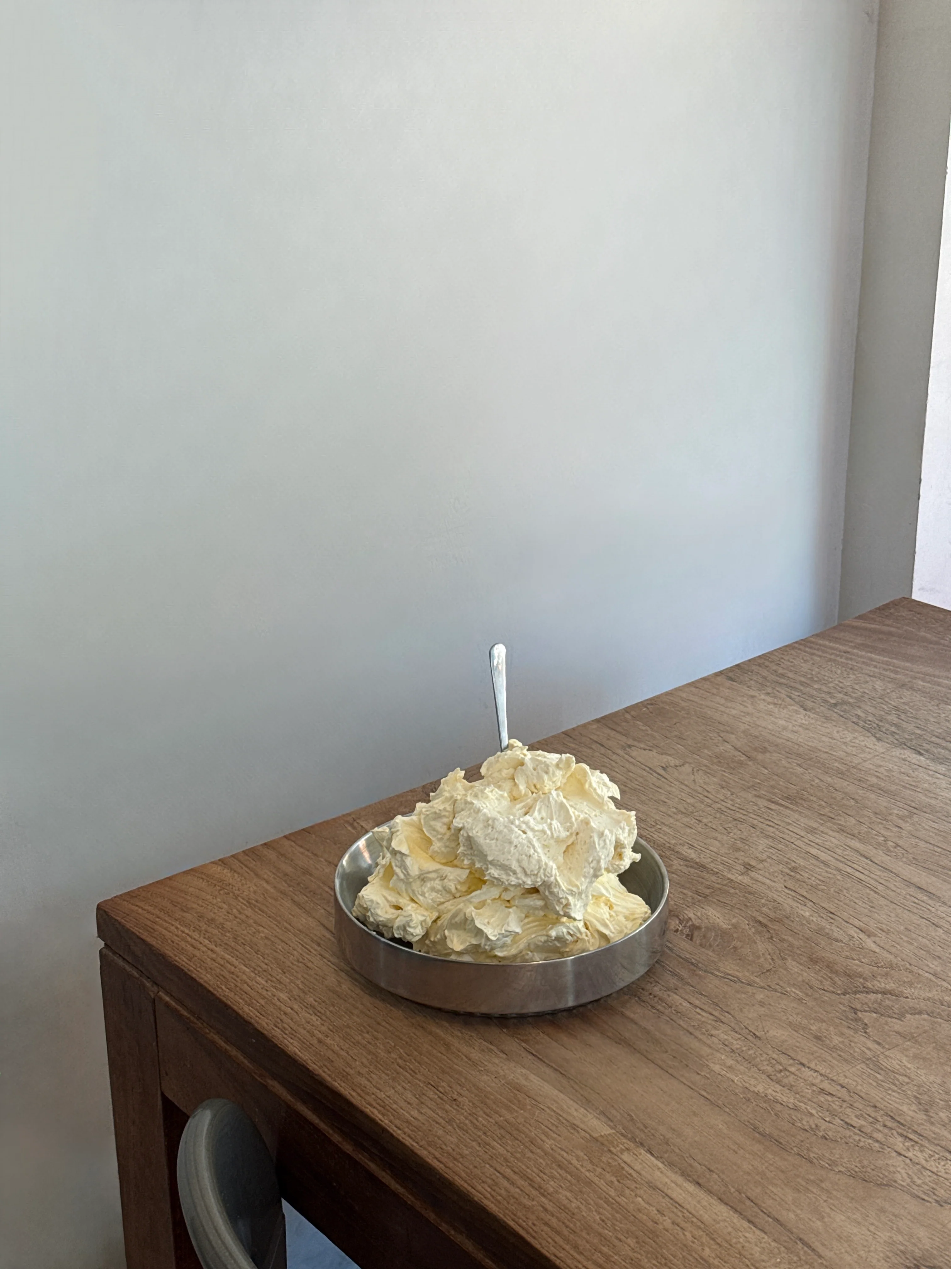 A bowl of freshly churned plantbased cream on a wooden table